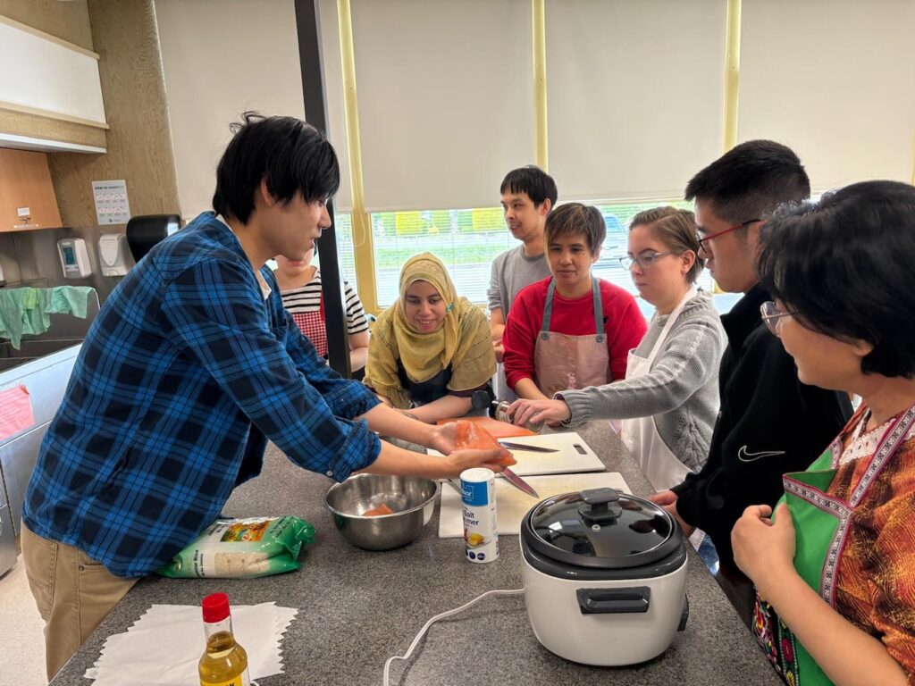 Volunteer showing people how to make salmon.